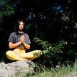 photo of woman doing yoga while sitting on rock