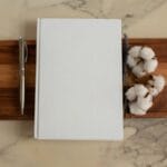 white notebook with pen and cotton flowers on tray