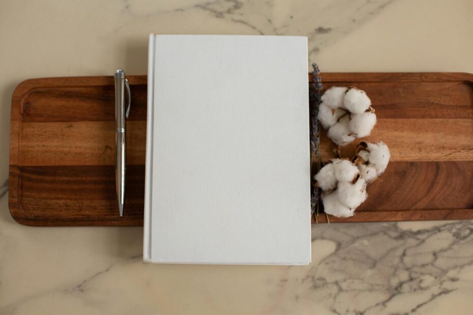 white notebook with pen and cotton flowers on tray