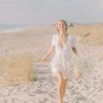 woman in white dress running on the sand