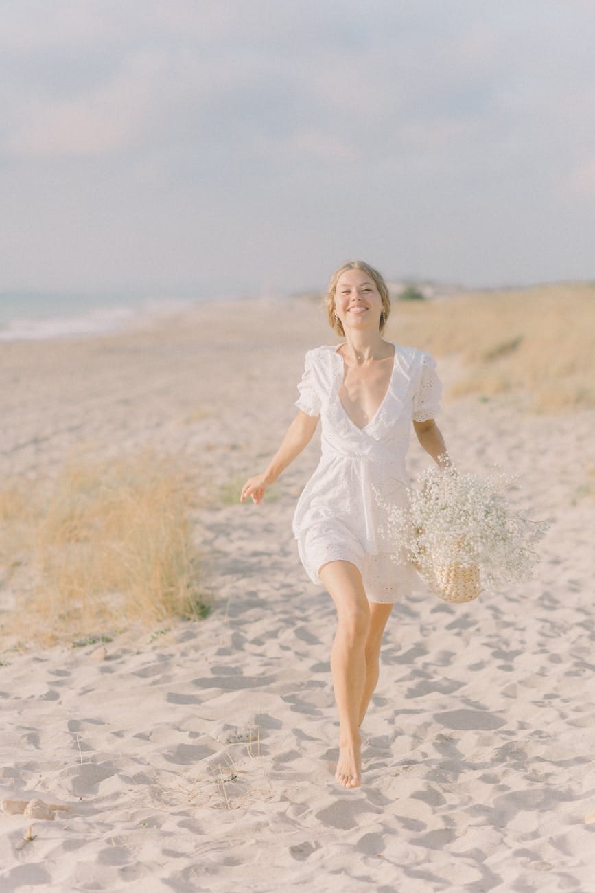 woman in white dress running on the sand