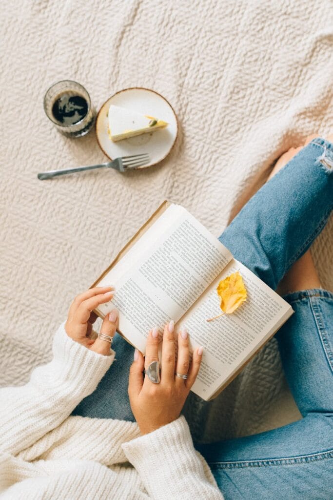 person in blue denim jeans reading book