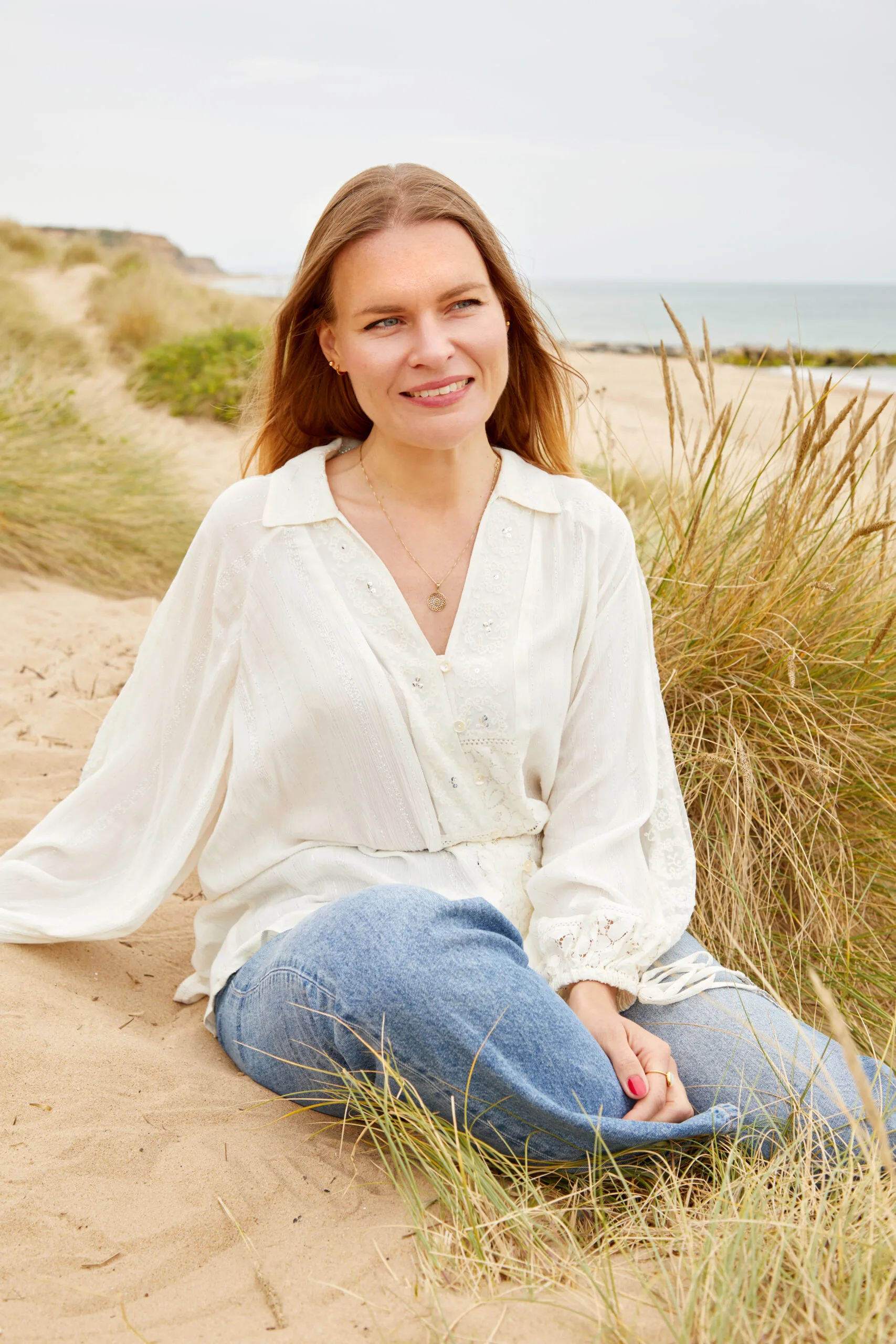 Justyna Rossy, astrologer, smiling and seated in a cream blouse